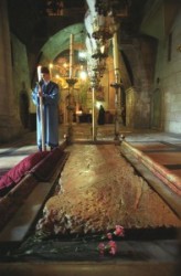 Szentsír templomban a bebalzsamozás kövénél  örmény szerzetes várja a patriarchát. A bebalzsamozás köve felett nyolc lámpa van. A megkenés kövét eltakaró márvány lap mellett virág van.                
